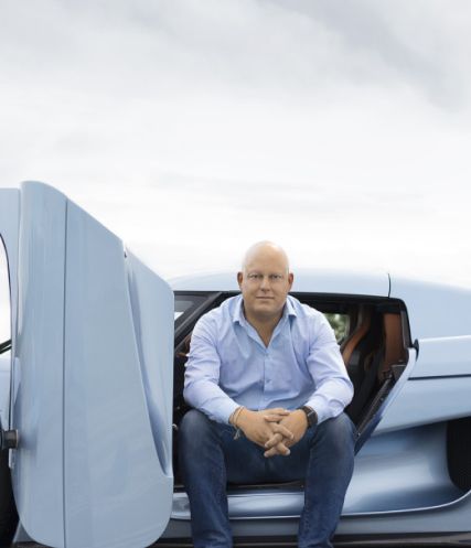 A man sitting in the door opening of the car